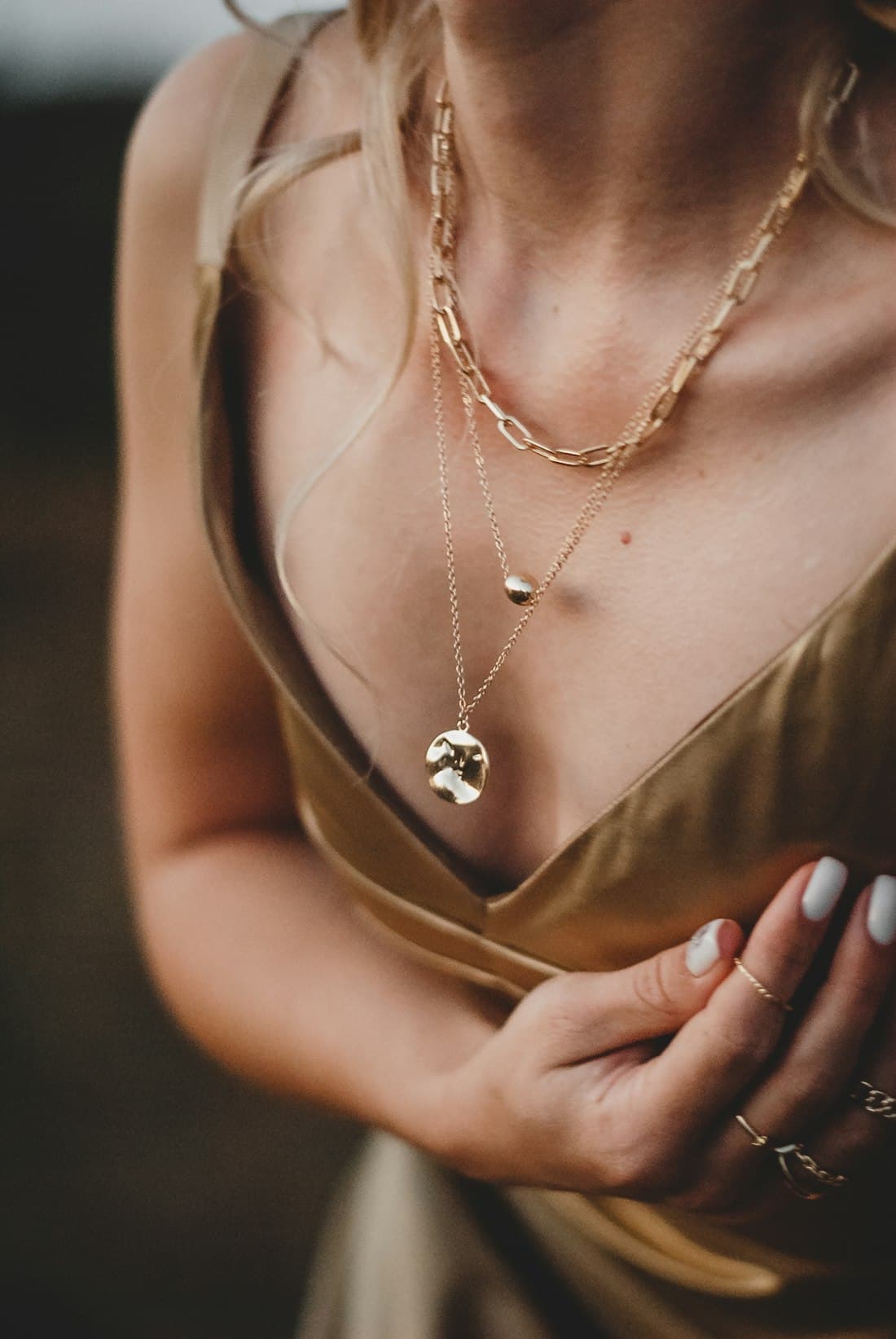 Colares de ouro em camadas sobre vestido dourado — catálogo Áurea
